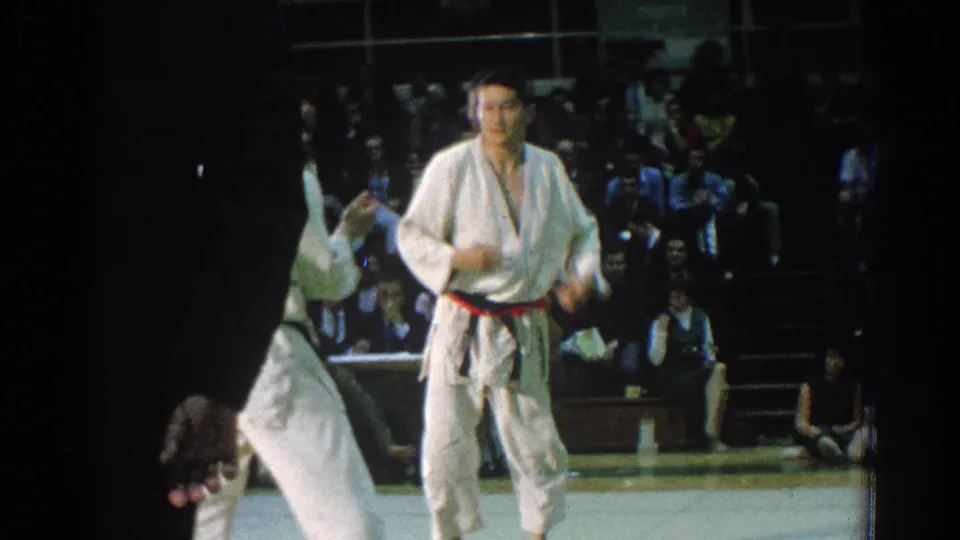 A 1966 San Gabriel judo exchange shows one competitor upright as another is thrown or lifted near a dark-clothed official.