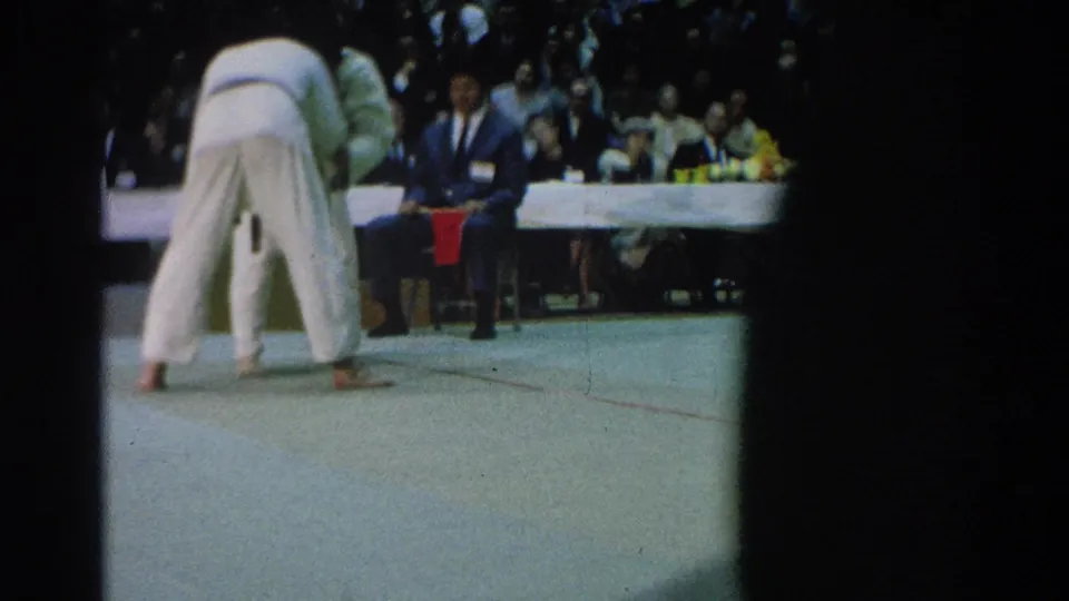 1966 San Gabriel footage appears to show two judo competitors in white gi engaging on an indoor mat before officials and a crowd.
