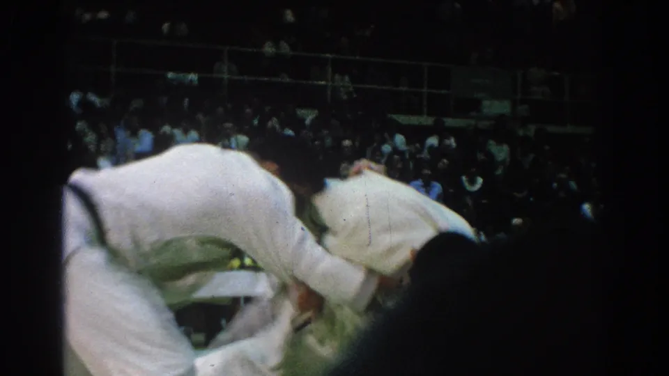 During the San Gabriel match, two judo athletes lean into a close grip, their motion blurred by handheld 8mm filming.