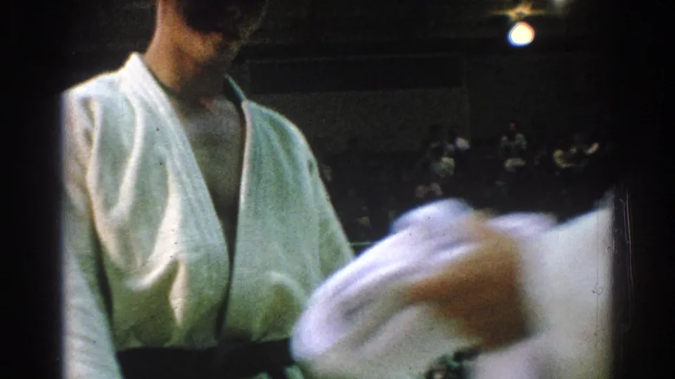 Close handheld view of a white-gi competitor during a 1966 indoor martial arts contest in San Gabriel.