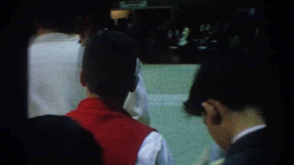 Spectators or officials seen from behind as white-gi competitors stand near the mat at the 1966 San Gabriel contest.