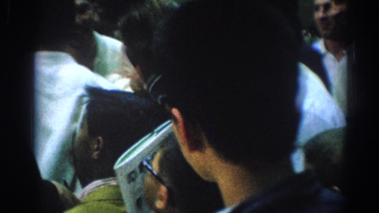 Close crowd view with a man holding a folded paper near people in white shirts.