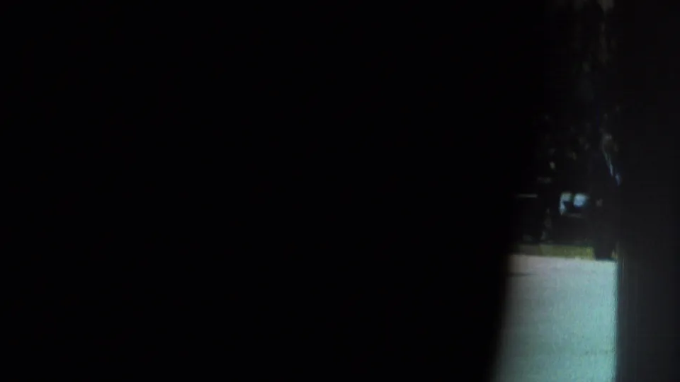 Obscured 1966 8mm frame from San Gabriel footage, showing mostly darkness with a narrow bright opening and indistinct outdoor or entryway detail.