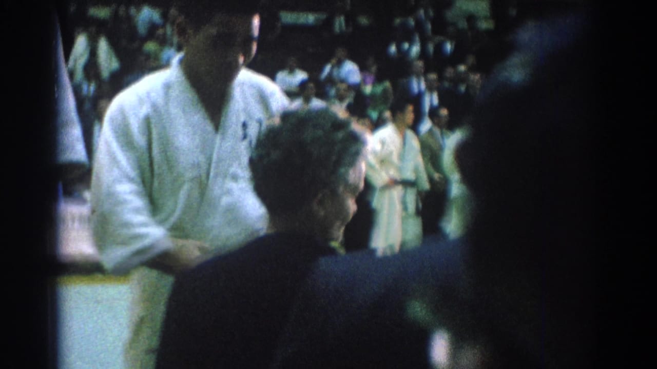 An official faces a karate competitor in a white gi during an award presentation.