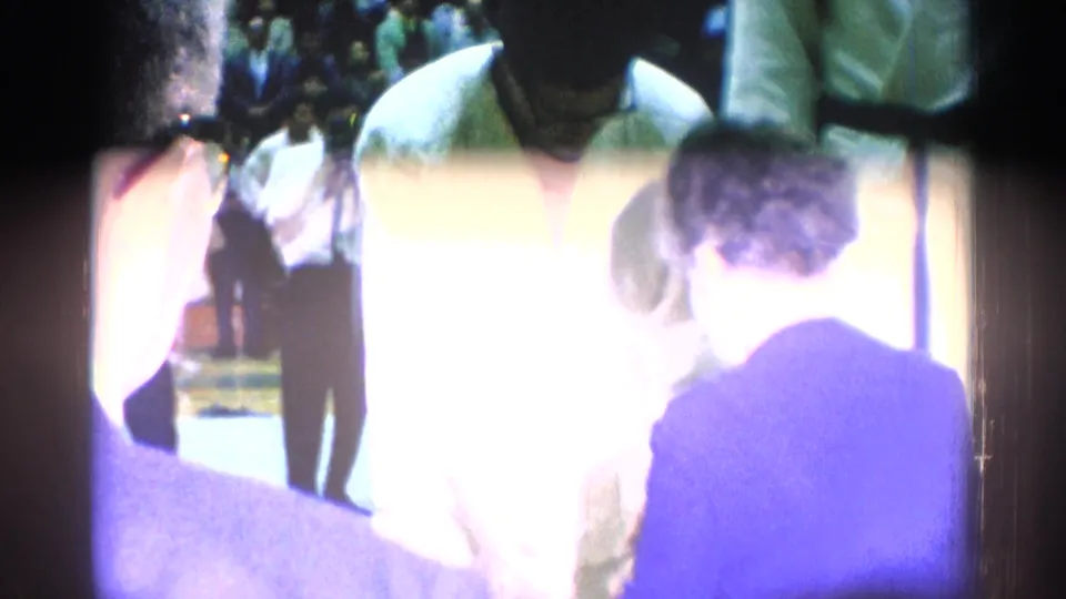 A flare-heavy 8mm frame partially obscures the 1966 karate award ceremony, with figures still visible around the podium area.