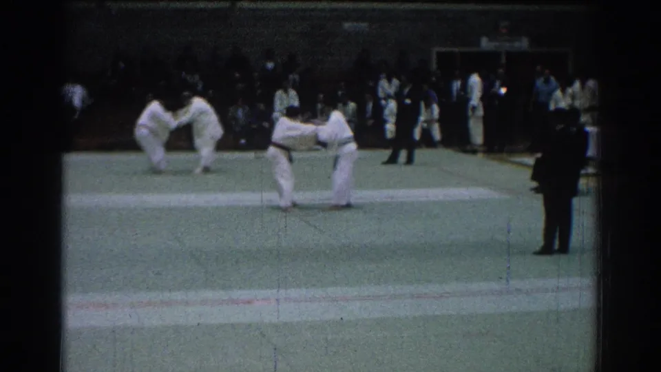 During the San Gabriel judo match, one competitor appears to execute a throw as another pair of athletes prepares nearby.