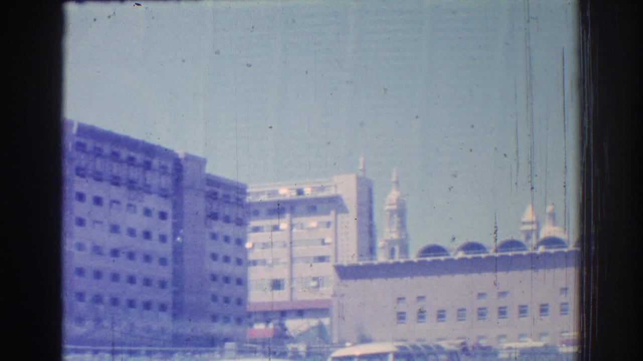 San Gabriel urban buildings and a tower-like structure seen from a moving vehicle in 1966 footage.