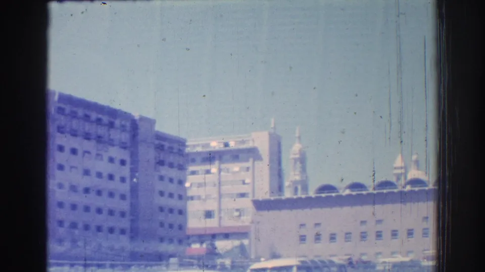 San Gabriel urban buildings and a tower-like structure seen from a moving vehicle in 1966 footage.