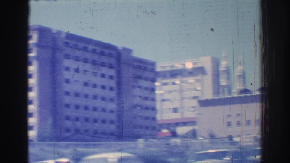 Moving-car view of San Gabriel buildings, street edges, and bright sky in 1966 home-movie footage.