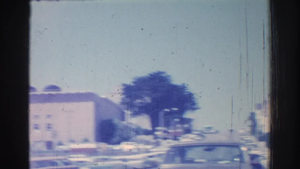 San Gabriel street view with parked cars, trees, and a low building seen from a moving vehicle in 1966.