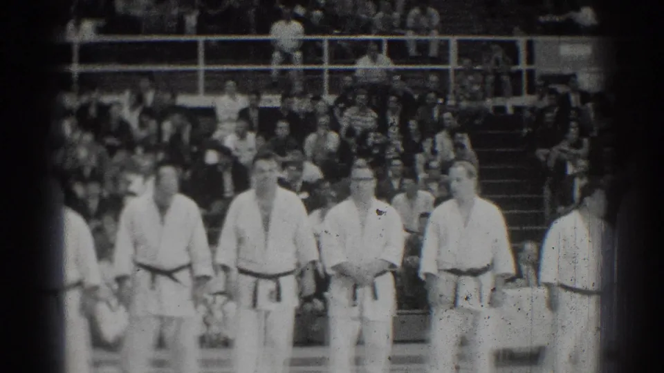Male judokas in a San Gabriel gym stand before spectators during a 1966 championship lineup.