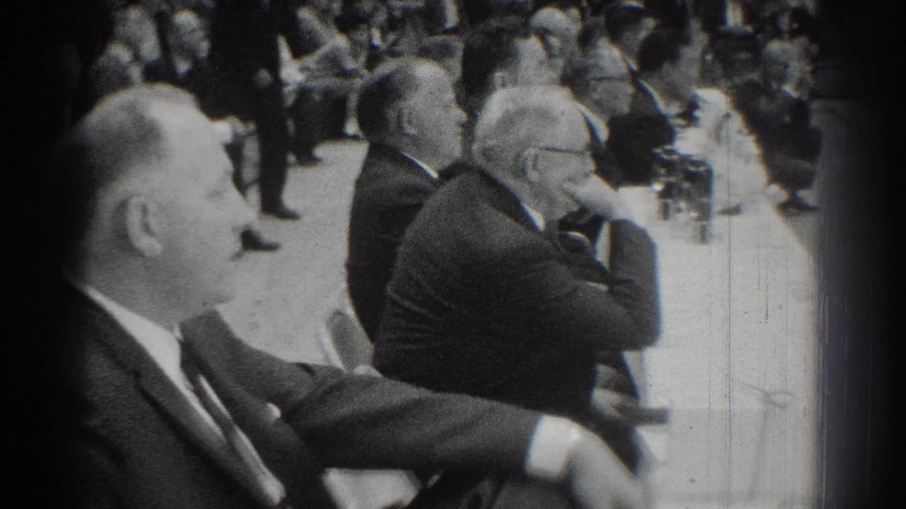 1966 San Gabriel home-movie frame of suited judges at a long table watching activity inside a gymnasium.