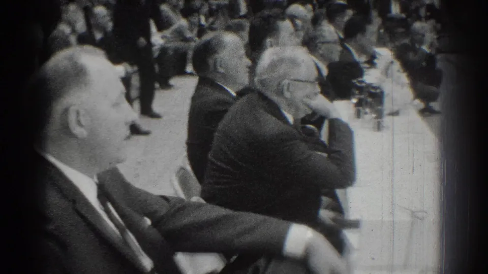 1966 San Gabriel home-movie frame of suited judges at a long table watching activity inside a gymnasium.