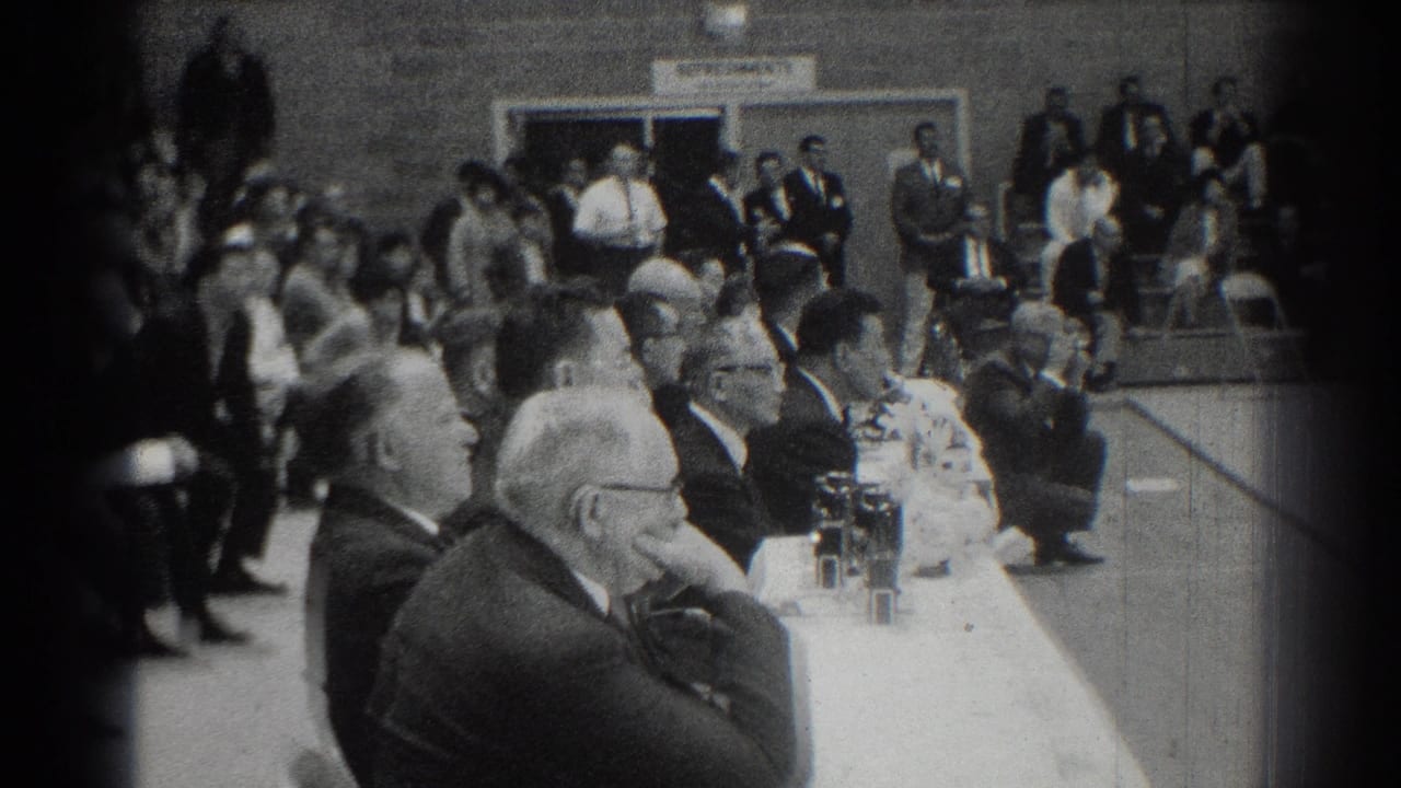 Judges sit beside spectators in a gymnasium during a karate competition.