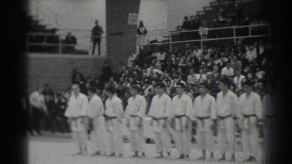 A wider 1966 San Gabriel judo competition view shows athletes lined across the mat, with spectators and venue architecture in the background.