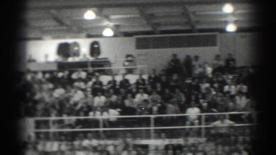 Crowded bleachers in a San Gabriel gymnasium, filmed from an 8mm home-movie perspective in 1966.