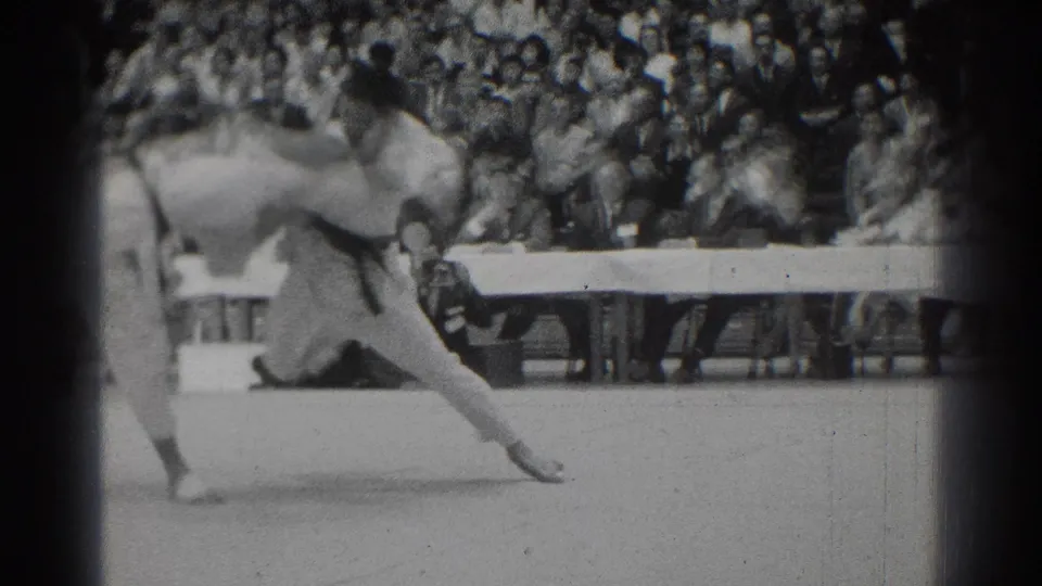 One competitor appears to be lifted or thrown during the San Gabriel judo match, with the audience watching behind the mat.