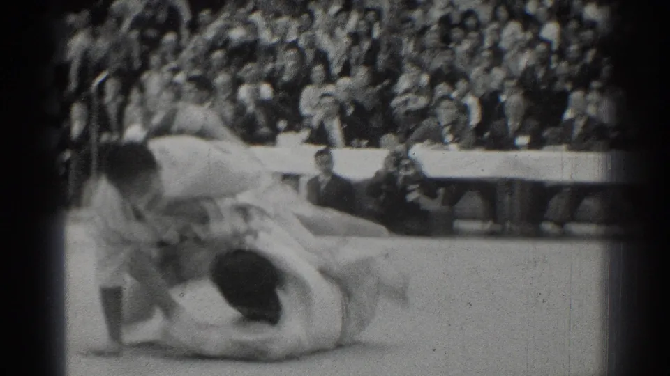 A 1966 San Gabriel judo match moment shows one competitor on the mat while the other bends over him, with spectators behind the action.