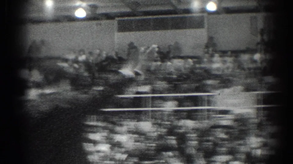 The final frame gives a soft, handheld wide view of the gymnasium, with audience rows, railings, and bright overhead lights during the 1966 judo event.