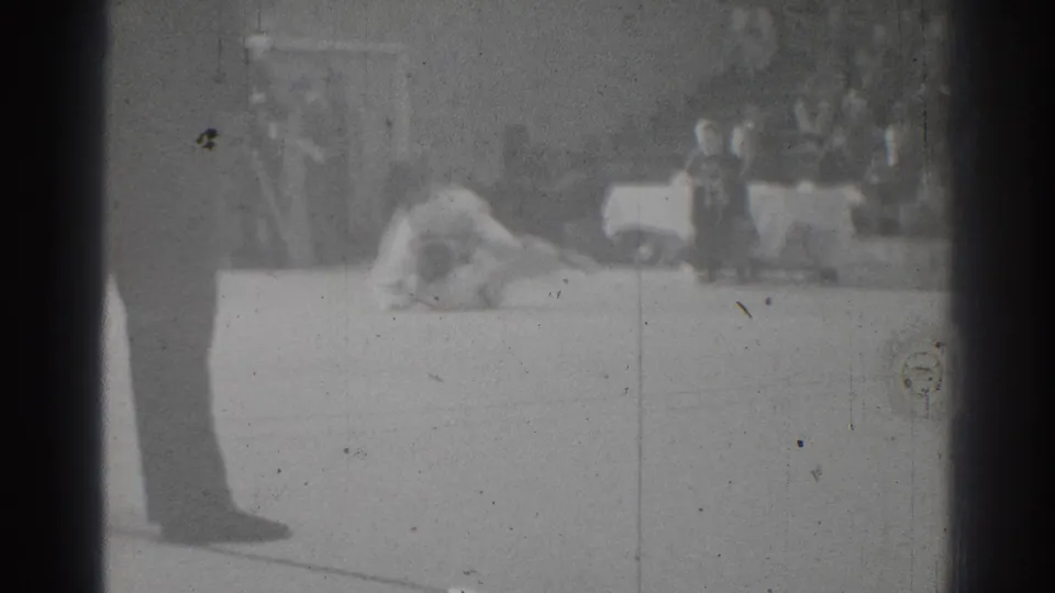 During the San Gabriel karate match, one competitor appears to land on the platform while suited figures stand near the edge.