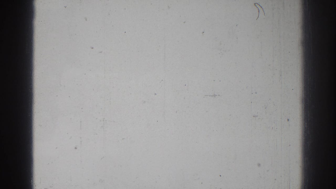 Pale blank 8mm frame with dark vertical frame bars, dust specks, and fine scratches.