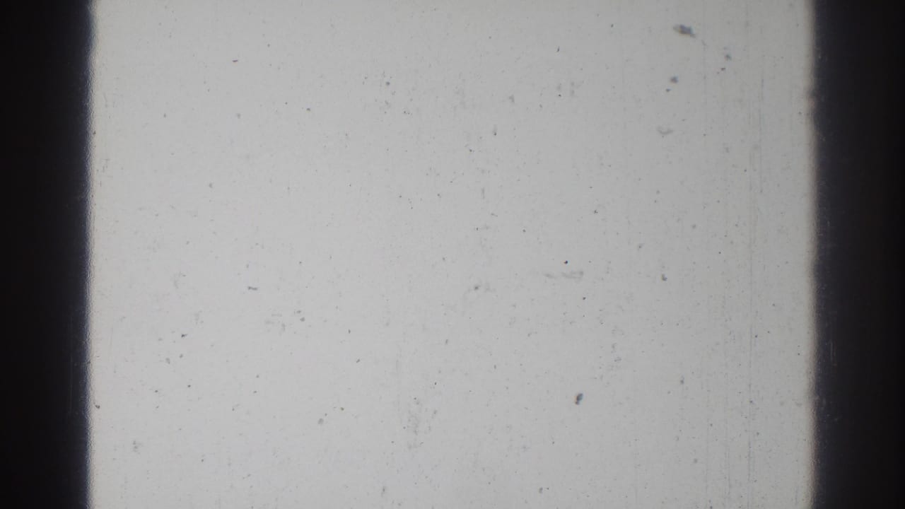 Mostly blank 8mm frame with dark film borders, dust, and scratches.
