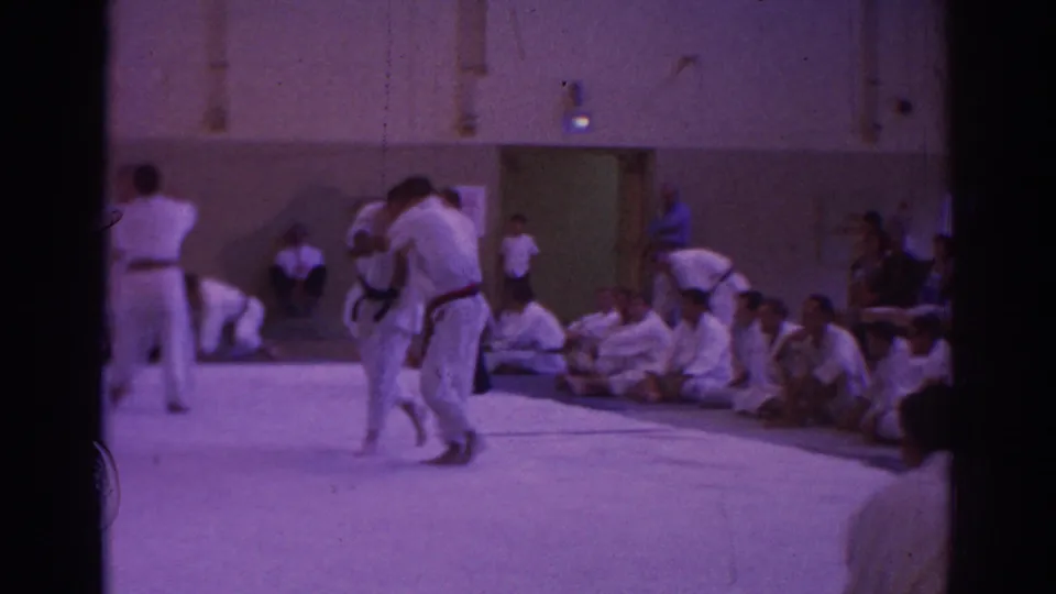 Temple City 1966 home-movie frame of two martial artists standing in close engagement during an indoor competition.