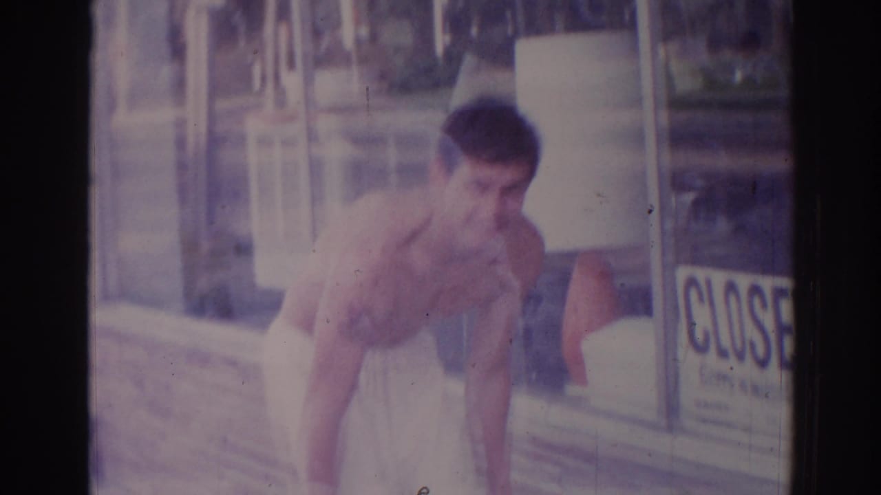A shirtless man in a towel leans outside a Temple City storefront, with a CLOSED sign visible in the window.