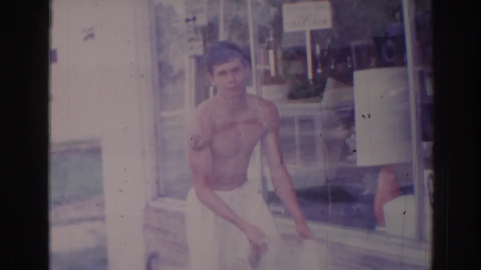 At the end of the 1966 Temple City clip, the shirtless man in a towel faces toward the camera outside the closed storefront.