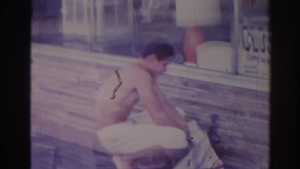 The man leans forward over laundry or cloth on the sidewalk outside a Temple City storefront, with the CLOSED sign partly visible.