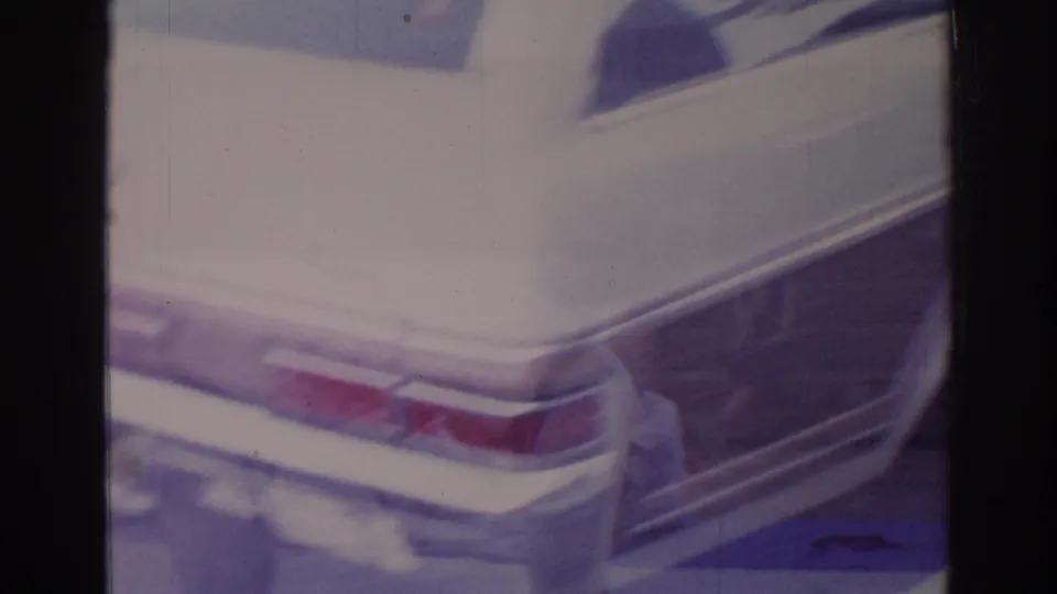 Temple City 1966 frame showing the rear of a pale American sedan with tail lights, chrome trim, bumper detail, and faded 8mm color.