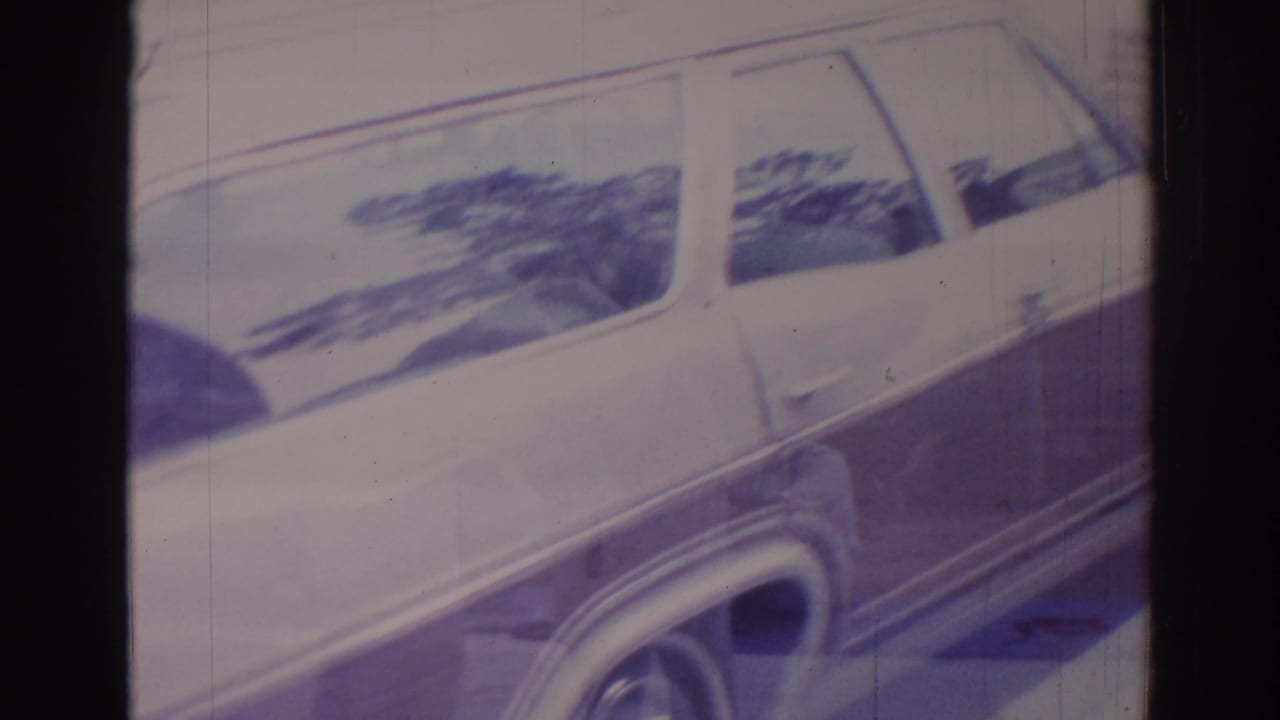 Close view of a light-colored station wagon on faded 8mm film.