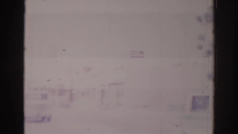 Faded 8mm view of a quiet Temple City street area in 1966, with low buildings and indistinct road activity in soft focus.
