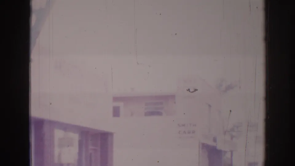 Temple City, California 1966 home-movie frame with a hazy storefront edge, partial signs, film scratches, and dark 8mm gate borders.