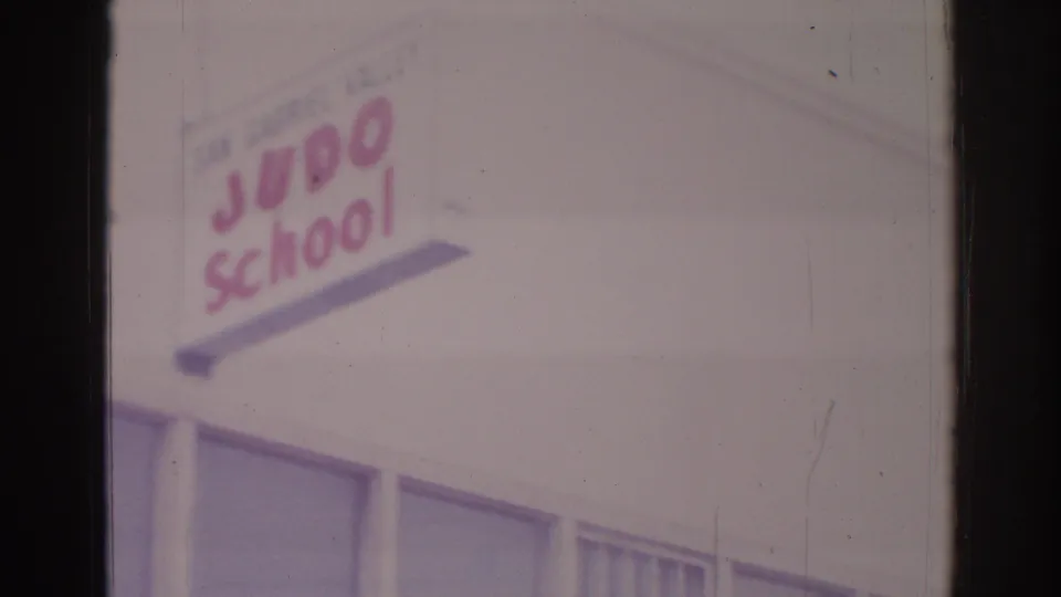 Temple City building exterior with San Gabriel Valley Judo School sign and upper windows, captured on 1966 8mm film.