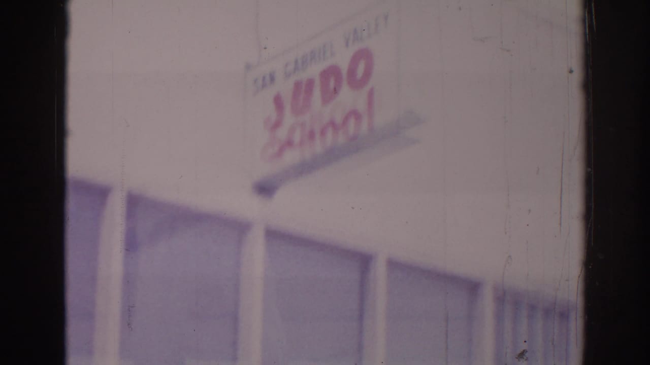 Upper facade with judo school sign and rows of windows.