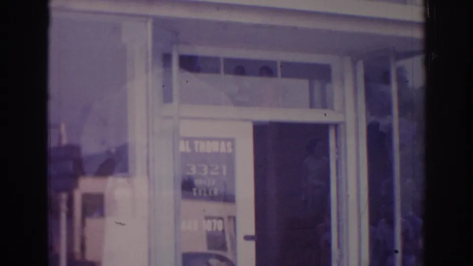 1966 Temple City judo school entrance with the sign overhead, glass panels, and a faint person visible inside the doorway.