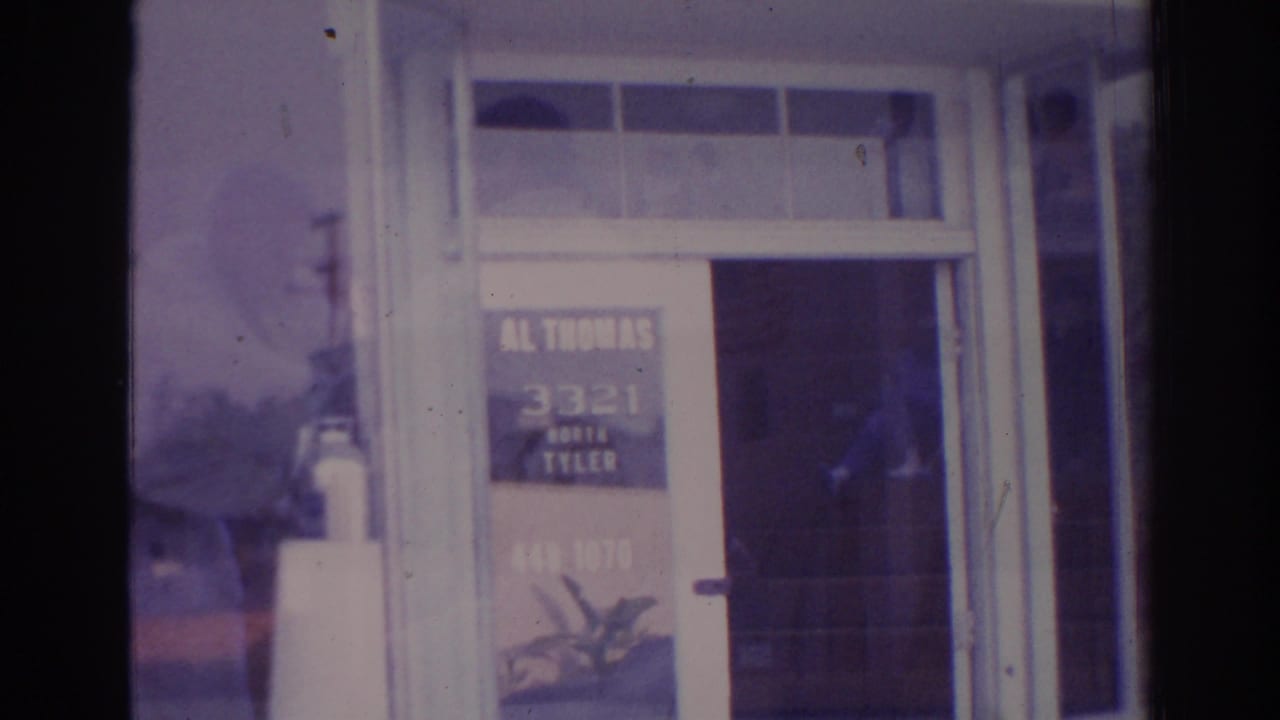 Glass door and window with business lettering and a dark reflected figure near the entrance.