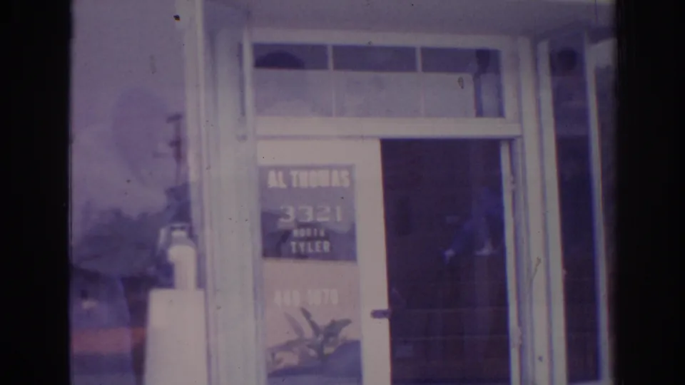 Temple City commercial doorway on 8mm film, showing painted lettering, white trim, and a reflected man near the glass.