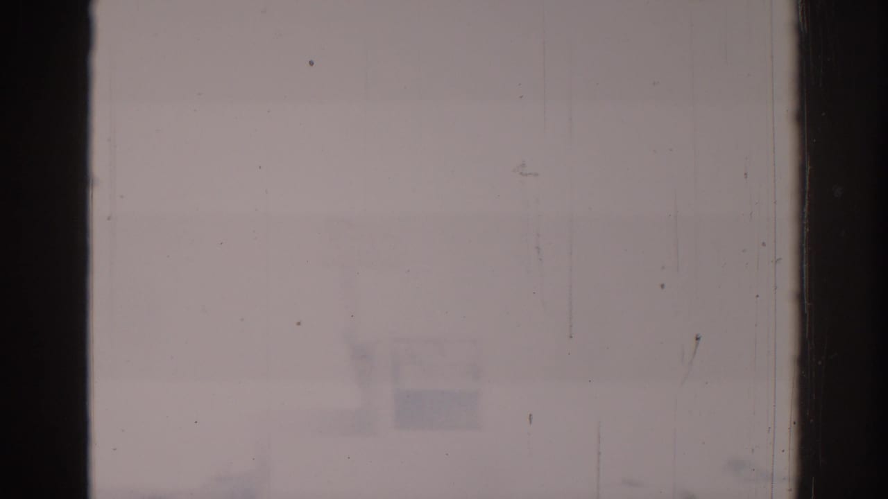 Mostly overexposed frame with faint street details and dark vertical film edge.