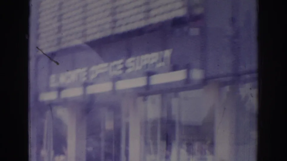 Temple City-area 1966 bus-window view with a blurred office supply storefront sign and street-facing glass.