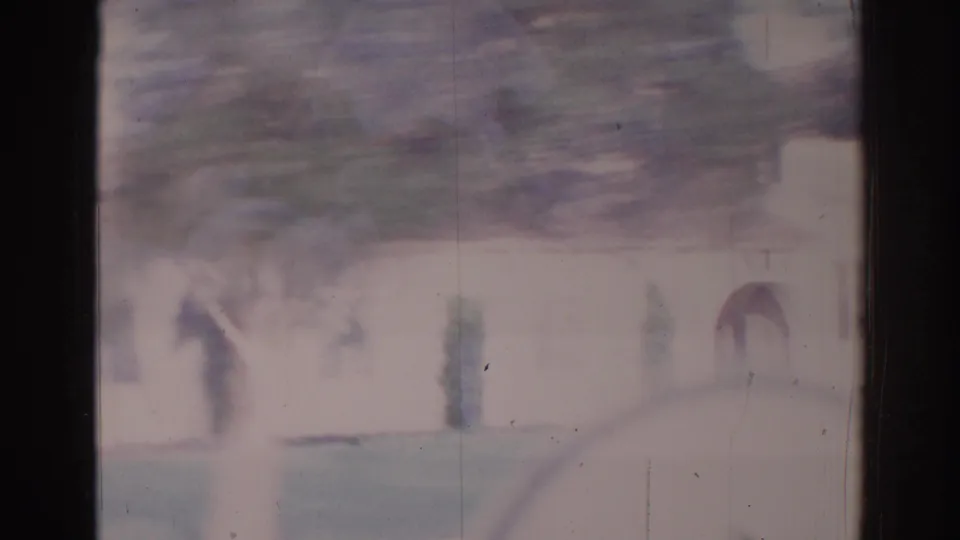 Faded 8mm view of a Temple City residential frontage with trees and a car-window reflection, softened by motion and exposure.