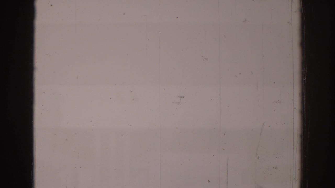 Overexposed 1966 8mm frame with pale film area, visible dust, scratches, and dark vertical frame bars.