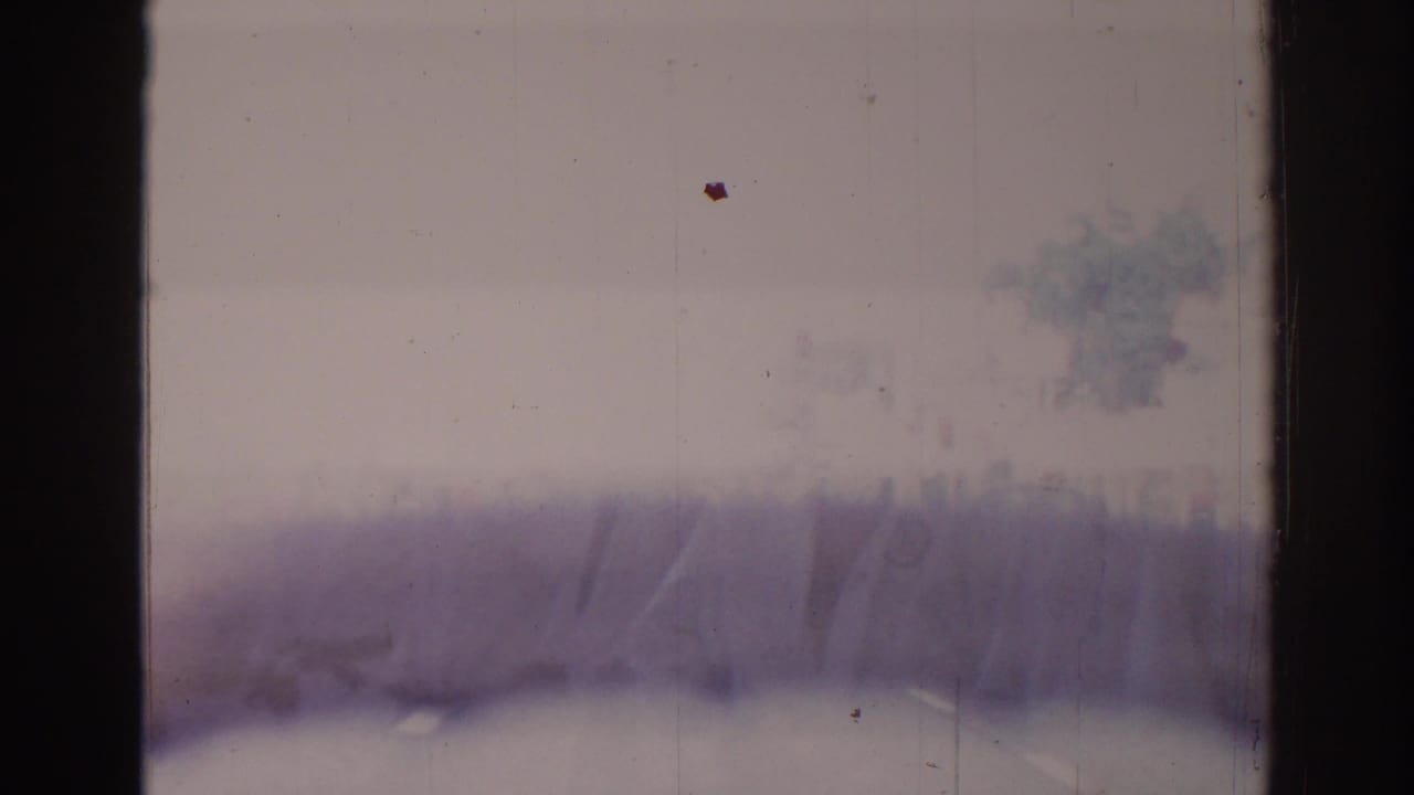 Faded exterior-like blur or light leak with film scratches and frame borders.