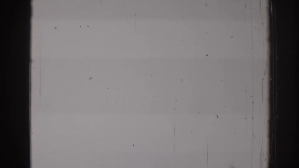 A late frame from the 8mm clip showing a gray exposed field with black borders, dust, scratches, and no clear figures.