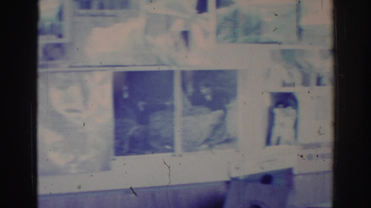 Overexposed film frame with a dim interior and indistinct room details.