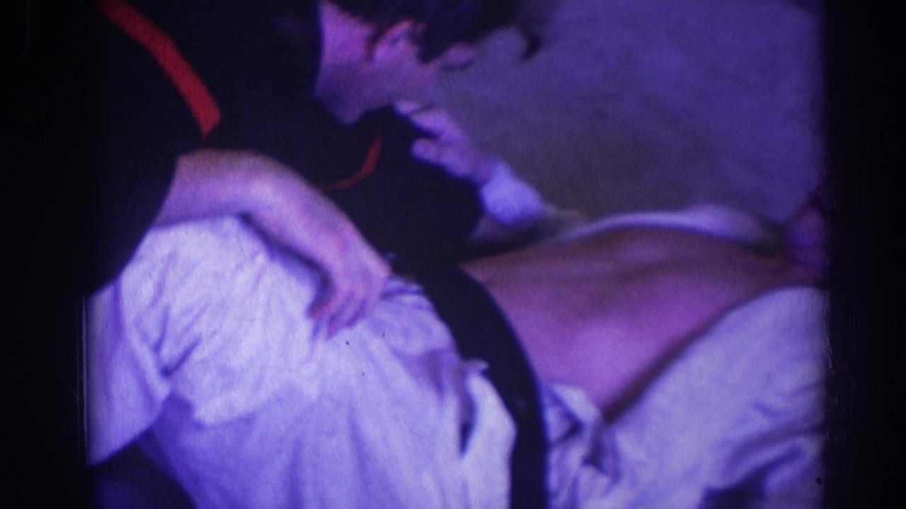 Two men in martial arts uniforms grapple on the floor at close range.