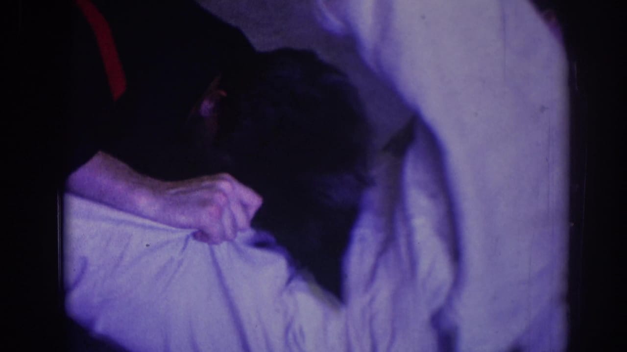 Man in a dark uniform leans over a man in a white gi during a floor hold.