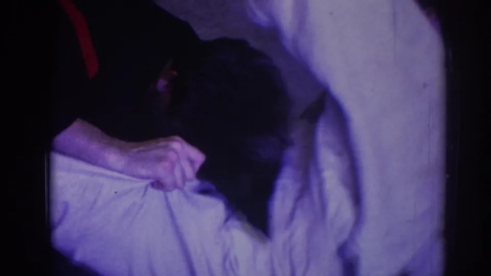 A man in a dark martial arts uniform leans over an opponent in a white gi during close floor grappling in the 1966 Temple City clip.