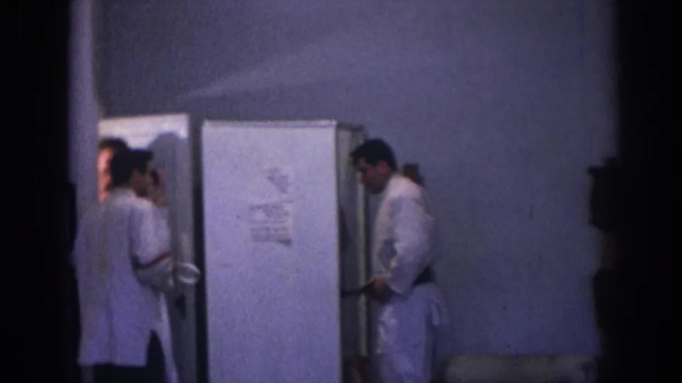 1966 Temple City home-movie frame with several young men near a doorway and a man in a white gi standing in the room.